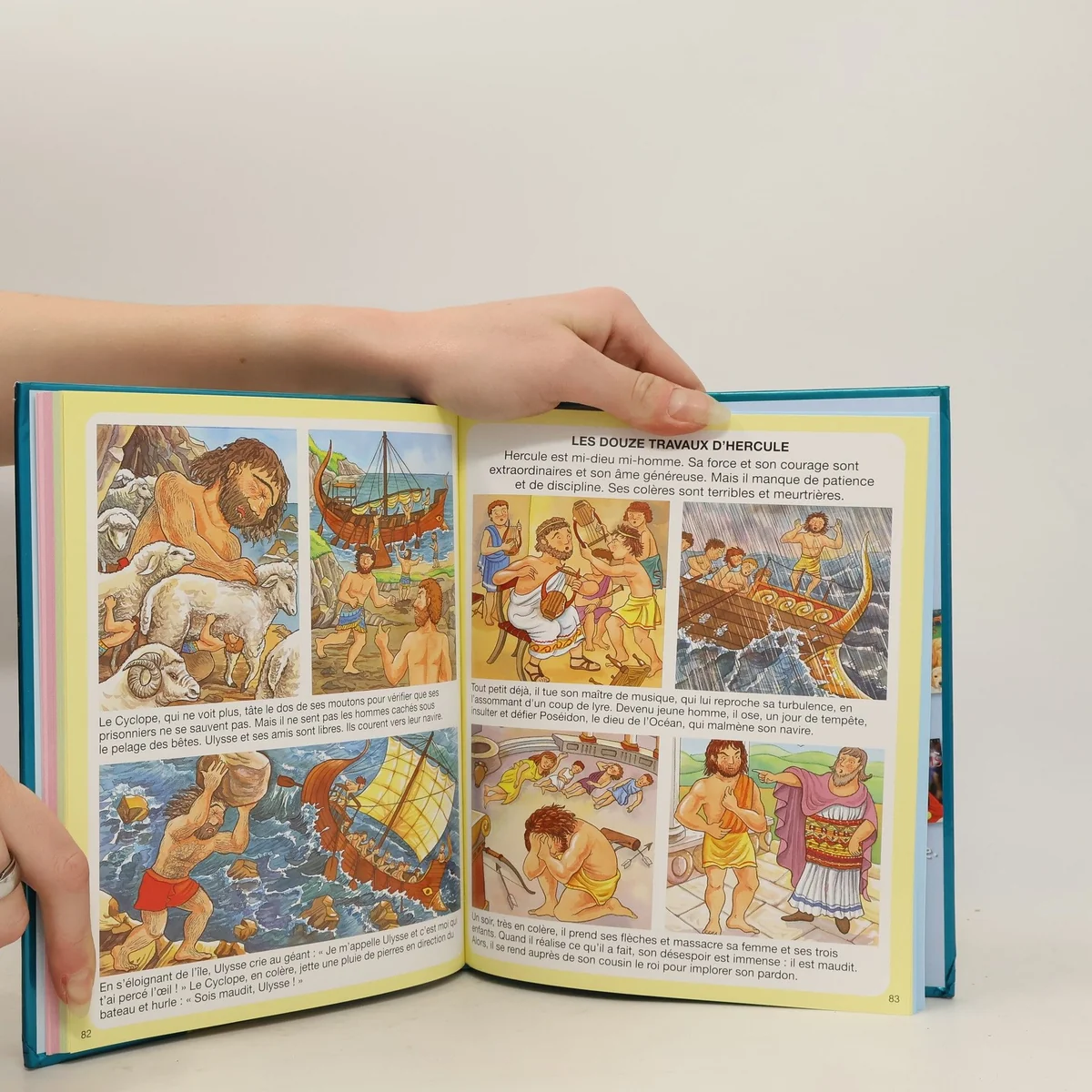 Open illustrated children’s book spread about the twelve labours of Hercules, with colorful comic-style scenes and French explanatory text.